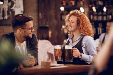 Happy waitress serving her customer with a beer in a pub. 