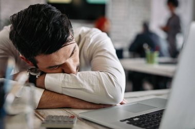 Depressed young businessman taking a break after working on laptop in the office. 