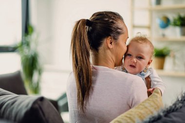 Young mother holding her baby boy while spending time together at home. 