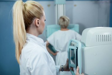 Female technician taking medical X-ray of a patient at clinic. 