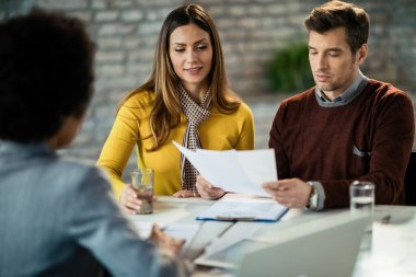 Couple reading terms of a contract while having a meeting with insurance agent in the office. 