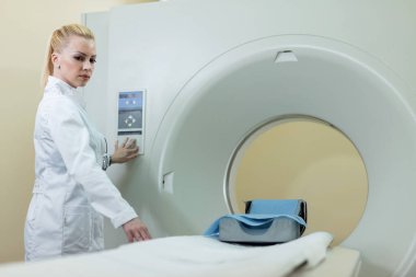 Female radiologist preparing CT scanner for patient medical examination in the hospital. 