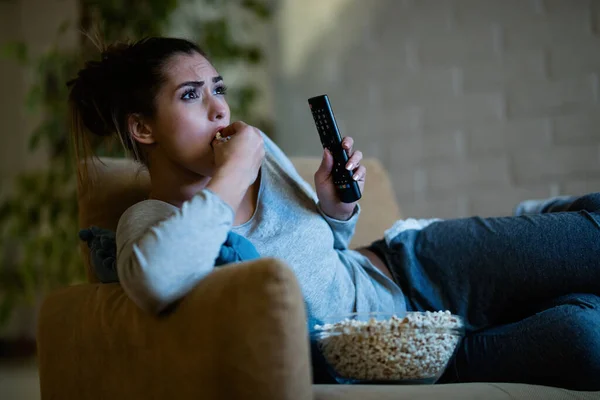 Молодая Напуганная Женщина Смотрит Телевизор Ест Попкорн Вечером Дома — стоковое фото