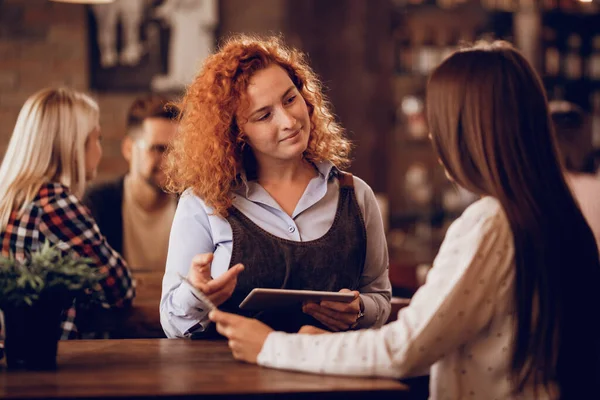 Smiling Waitress Using Digital Tablet While Talking Guest Taking Her — Stockfoto