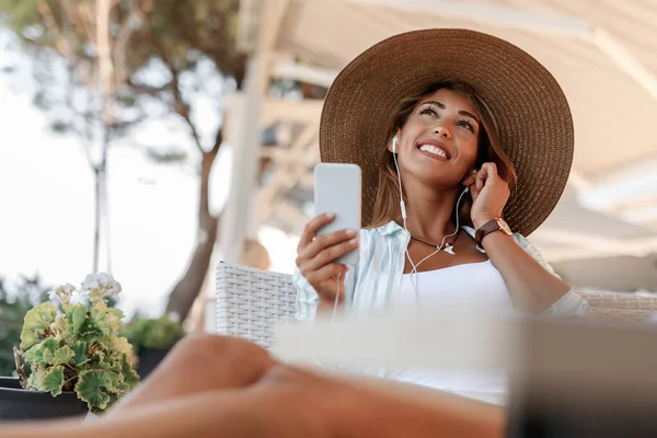 Smiling Pensive Woman Using Smart Phone Listening Music While Relaxing — Stockfoto