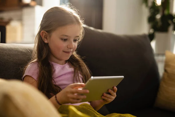 Smiling Little Girl Reading Touchpad While Sitting Sofa Relaxing Living — Stockfoto