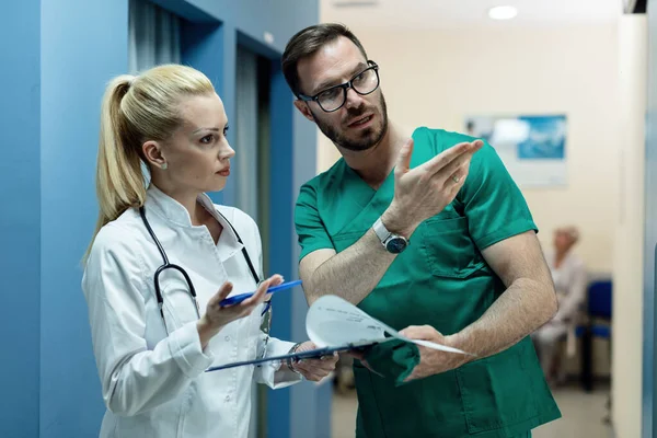 Two Doctors Discussing Examining Medical Reports Patient While Standing Hallway — Foto de Stock