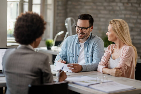 Happy couple going through paperwork with their insurance agent during the meeting in the office.