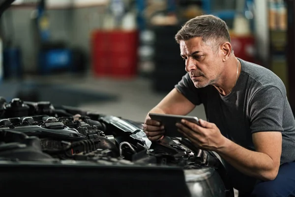 Car Mechanic Using Digital Tablet While Repairing Analyzing Engine Auto — Fotografia de Stock