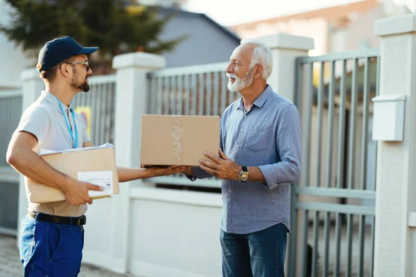 Young Courier Making Home Delivery Giving Package His Senior Customer — Stockfoto