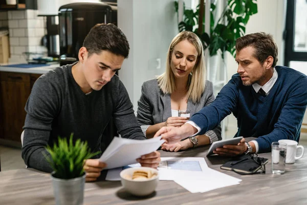 Real Estate Agent Explaining Young Couple Terms Contract While Having — Fotografia de Stock