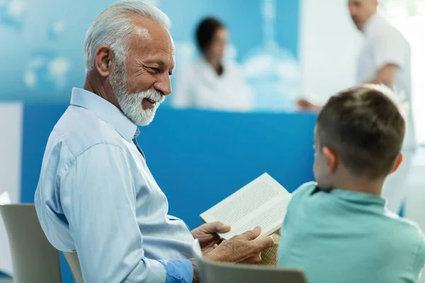 Happy Senior Man Reading Boo Communicating His Grandson Hospital Waiting — Foto Stock