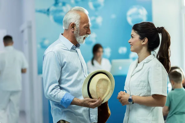 Young Happy Doctor Talking Senior Patient While Standing Corridor Clinic —  Fotos de Stock