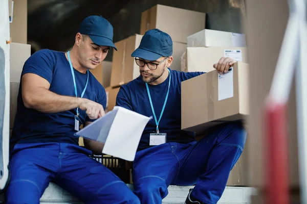 Two Delivery Men Reading Paperwork While Preparing Packages Shipment — Foto Stock