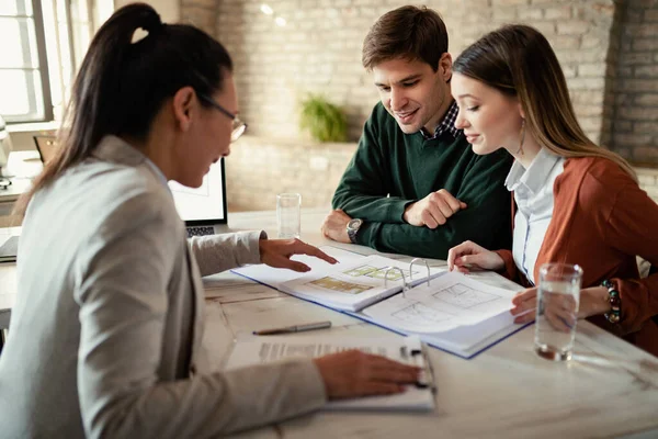 Young Couple Real Estate Agent Analyzing Blueprints Meeting Office Focus — Zdjęcie stockowe