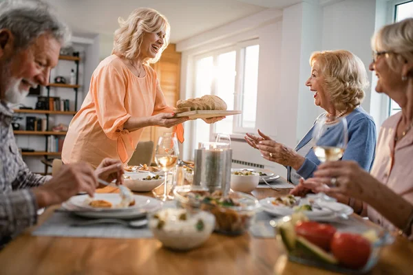 Happy Mature Woman Having Lunch Her Friends Bringing Bread Dining — Zdjęcie stockowe