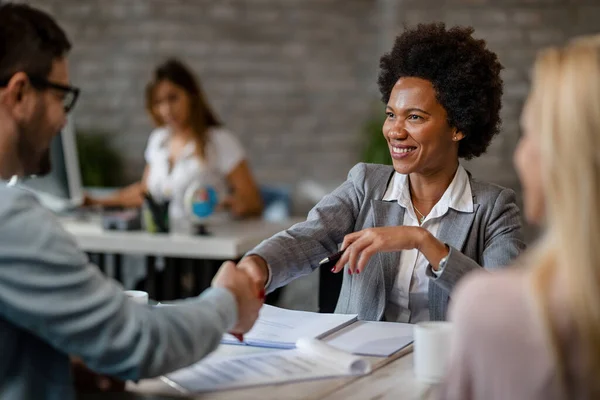 Happy African American Insurance Agent Greeting Her Clients Handshaking Them — ストック写真