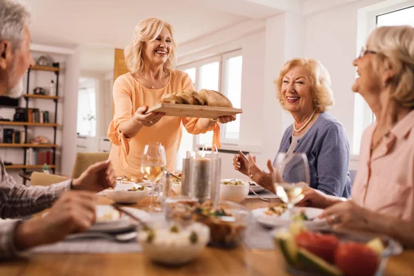 Happy Mature Woman Bringing Food While Having Lunch Her Friends — Stock fotografie