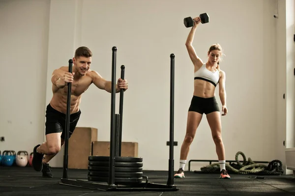 Muscular Build Man Doing Sled Push Exercise While Woman Listing — Fotografia de Stock