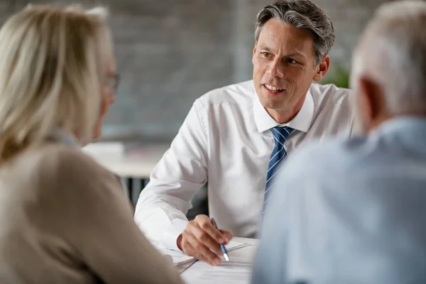 Smiling Financial Advisor Communicating Mature Couple While Writing Notes Meeting — Fotografia de Stock