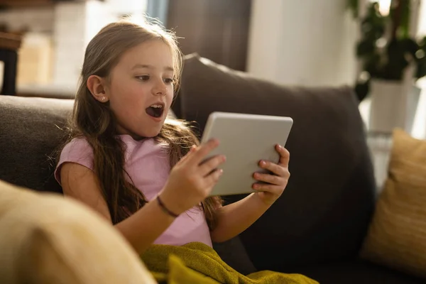 Small Girl Feeling Shocked While Using Digital Tablet Reading Something — Stockfoto