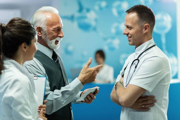 Happy Senior Businessman Touchpad Communicating Doctor While Standing Hallway Medical — Stockfoto