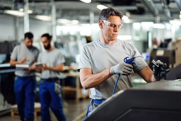 Factory worker using CNC machine while working in industrial facility. 