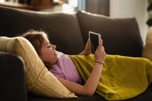 Μικρό Κορίτσι Χαλαρώνοντας Στον Καναπέ Και Χρησιμοποιώντας Touchpad Στο Σαλόνι — Φωτογραφία Αρχείου