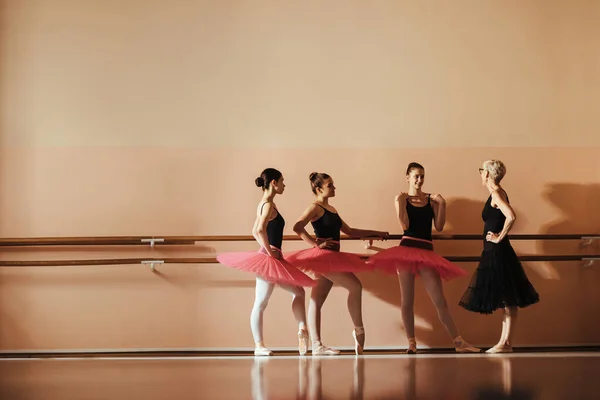 Full length of ballet instructor and ballerinas talking during a class at ballet school. Copy space.