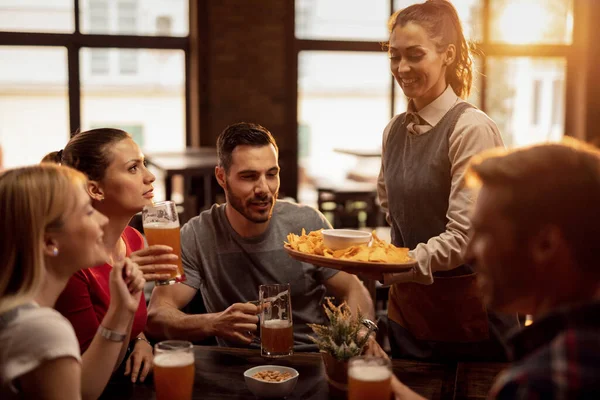 Група Щасливих Друзів Ють Пиво Таверні Офіціантка Подає Чіпси Начо — стокове фото