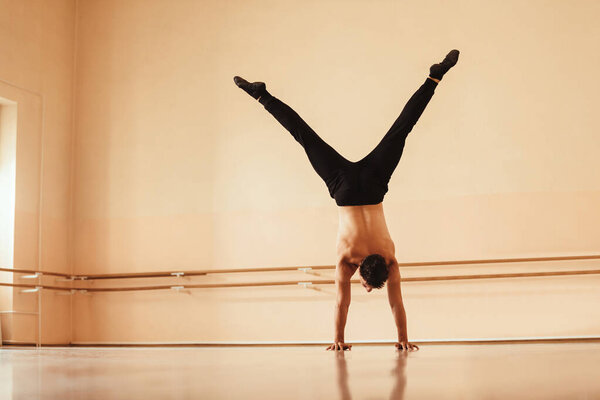 Rear view of a dancer exercising in a studio and doing a handstand. Copy space.