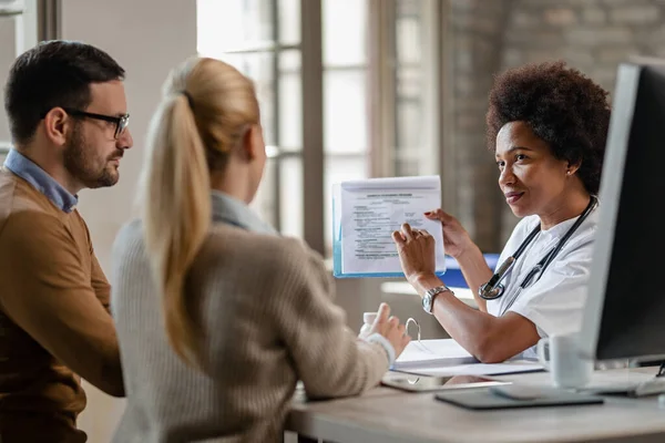 Black Female Doctor Talking Couple While Showing Them Test Results — Foto de Stock