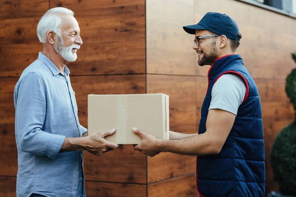 Smiling senior man receiving package from a delivery man.