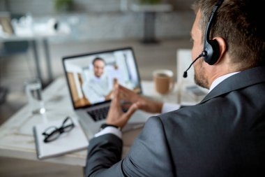 Close-up of entrepreneur using laptop while having online business meeting in the office. 