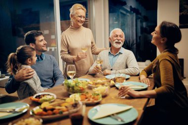 Happy senior couple enjoying while communicating with their family in dining room.