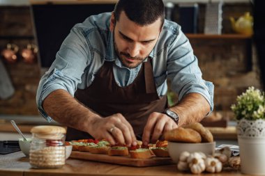 Genç adam sağlıklı yemek hazırlıyor ve mutfakta bruschetta yapıyor.. 