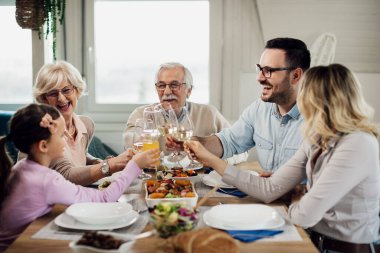 Mutlu geniş aile yemek masasında kadeh kaldırırken eğleniyor.. 