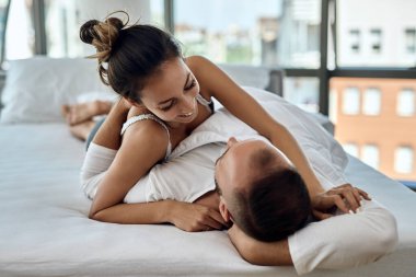 Young couple in love having fun while lying down on bed and communicating in the morning. 
