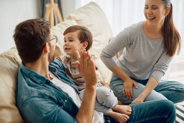 Happy little boy and his parents having fun together in the living room.