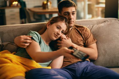 Young couple watching movie while relaxing on the sofa at home. 