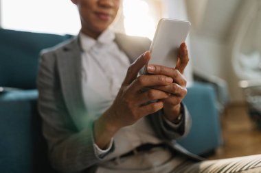 Close-up of black businesswoman typing message on smart phone. 