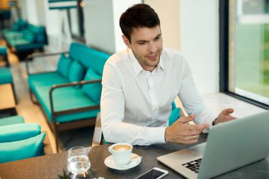 Mid adult businessman using computer and reading an e-mail while sitting in a cafe. 