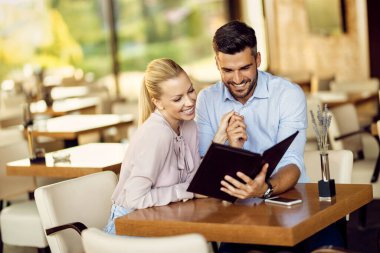 Happy couple  in love reading menu while holding hands in a restaurant. 