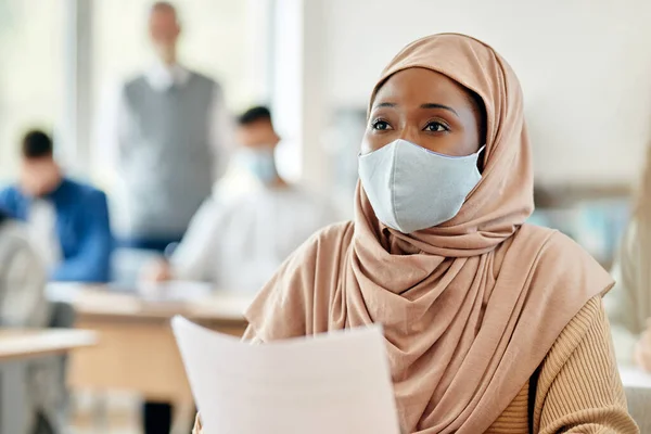 Black Muslim college student with face mask attending a class during coronavirus pandemic.