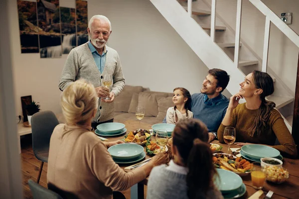 Happy Senior Man Holding Toast Family Lunch Home — Zdjęcie stockowe