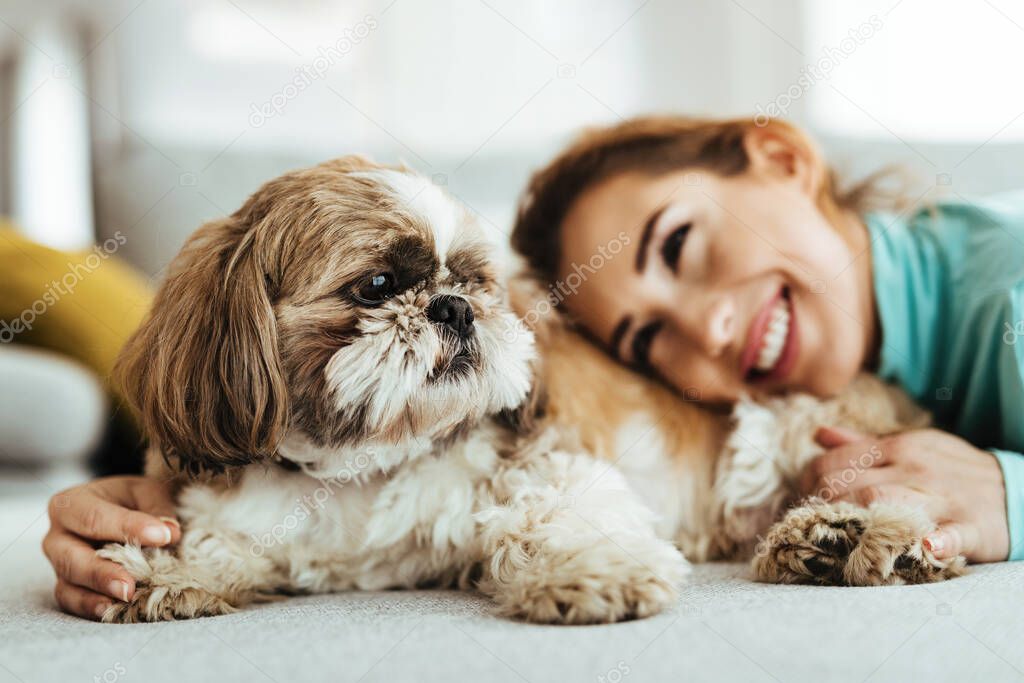 Happy woman and her dog enjoying while relaxing on the sofa. Focus is on dog. 