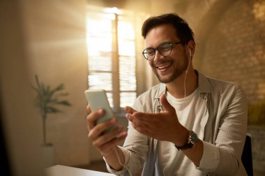 Young happy businessman using mobile phone while working in the office.