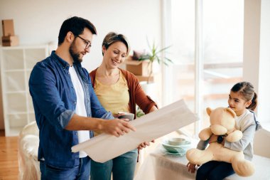 Happy family examining blueprints while moving into their new home. Focus is on woman.