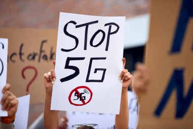Close-up of activist holding Stop 5G sign while protesting on city streets. 