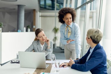 African American businesswoman talking with female colleagues while working on a meeting in the office.